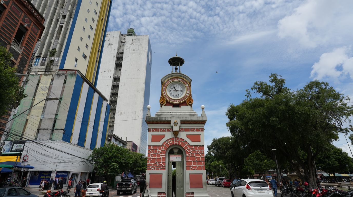 Relógio municipal no centro de Manaus, cercado por prédios e trânsito.