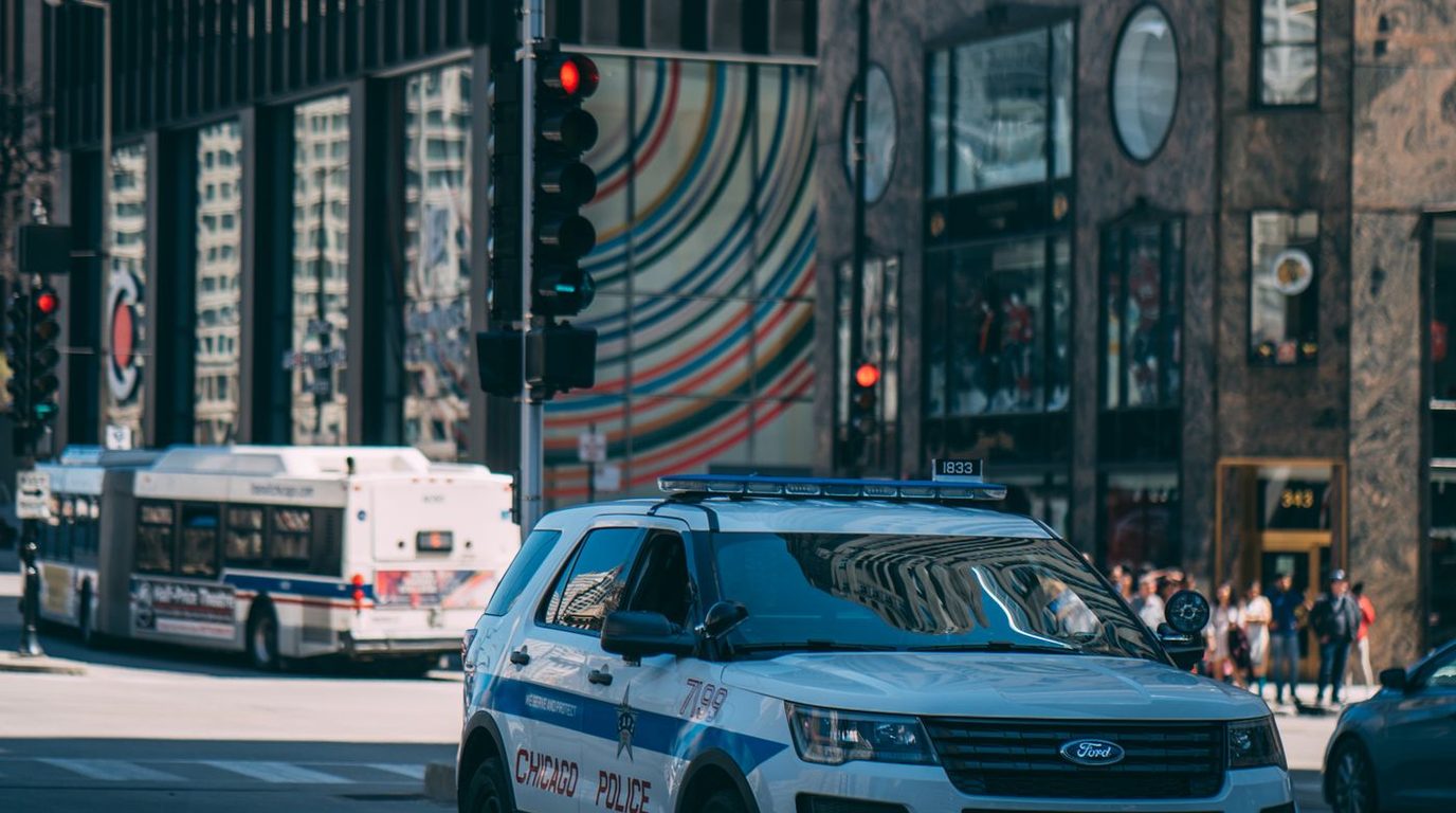 Via urbana com veículos em circulação e semáforo.