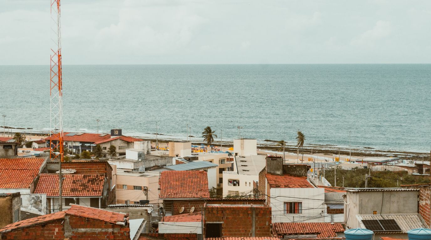 Casas de telhado vermelho e o mar ao fundo em uma cidade do litoral nordestino.