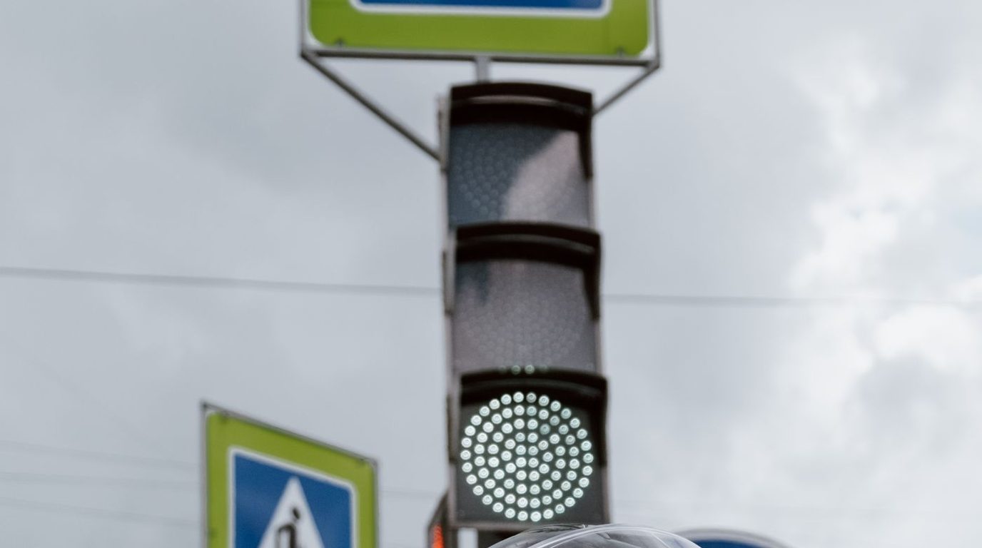 Semáforo e placa de faixa de pedestres em uma via urbana.